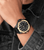 Herrenuhr am Handgelenk mit schwarzem Lederarmband und schwarz-goldenem Zifferblatt