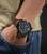 Herrenarmbanduhr am Handgelenk: dunkles Zifferblatt mit Chrono-Optik und braunem Lederband
