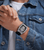 Am Handgelenk: Herren Uhr mit schwarzem Band und silbernem Gehäuse, skelettiertes Zifferblatt