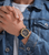 Herrenuhr am Handgelenk mit blauem Silikonband und goldfarbenem Chronographen-Zifferblatt