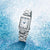 Damen-Armbanduhr im 3/4-Ansicht, rechteckiges Gehäuse, weißes Zifferblatt, Edelstahlband