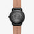 Montre homme avec boîtier noir, bracelet en cuir marron et fond gravé