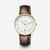 Montre Sternglas Naos pour homme : lunette dorée, cadran blanc, bracelet en cuir marron.