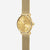 Montre pour femme de profil avec bracelet milanais doré et cadran rond beige clair