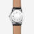 Fond de montre pour homme avec gravure circulaire et bracelet en cuir noir.