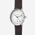 Montre homme avec bracelet en cuir marron et boîtier argenté, cadran blanc avec affichage de la date.
