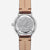 Dos de la montre homme : boîtier argenté avec motif de ville, bracelet en cuir marron, fond transparent.