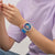 Armbanduhr am Handgelenk mit blauem Silikonband und bunten, kontrastreichen Zeigern.