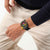 Swatch Armbanduhr am Handgelenk mit schwarzem Band und neonbunter Lünette