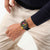 Swatch Armbanduhr am Handgelenk: schwarzes Band, buntes Chronograph-Zifferblatt und Lünette