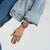 Armbanduhr am Handgelenk, blaues Silikonarmband, orangefarbenes Zifferblatt im Close-up