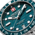 Detail der Herrenarmbanduhr: blau-grünes Zifferblatt, Indexe und Schweizer Kreuz