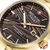 Nahaufnahme: goldene Armbanduhr mit dunkel gestreiftem Zifferblatt, Indexen und Datum 28