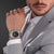 Herrenarmbanduhr am Handgelenk, schwarzes Zifferblatt mit Datumsanzeige und silberfarbenem Metallband