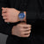 Herren-Armbanduhr am Handgelenk mit blauem Zifferblatt und Edelstahlarmband.