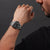 Herrenarmbanduhr am Handgelenk: schwarzes Zifferblatt mit Metallband und Lünette