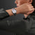 Damenuhr am Handgelenk mit silbernem Metallarmband und weißem Zifferblatt.