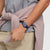 Dunkelblaue Swatch-Armbanduhr am Handgelenk mit Datumsanzeige und orangefarbenen Zeigern