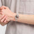 Transparente Armbanduhr am Handgelenk mit durchscheinendem Band und bunten Zeigern