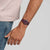 Armbanduhr am Handgelenk mit burgunderfarbenem Silikonband und Zifferblatt mit roten Akzenten