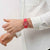 Swatch Damenuhr am Handgelenk mit rotem Herzarmband und rundem Herzmuster-Zifferblatt