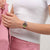 Damenuhr am Handgelenk mit rosafarbenem Gehäuse und farbig gemustertem Armband