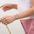 Armbanduhr am Handgelenk mit hellem bedrucktem Armband und farbigem Zifferblatt