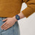 Armbanduhr am Handgelenk mit blauem Zifferblatt, gelben Leuchtindizes und blauem Silikonarmband.