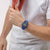 Armbanduhr am Handgelenk: blaues Armband, blaues Zifferblatt mit gelben Leuchtzeigern.