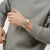 Beige Armbanduhr am Handgelenk, rotes Zifferblatt, silberne Lünette und Bandglieder