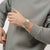 Beige Armbanduhr am Handgelenk, silbernes Band und rotes Zifferblatt mit Zeigern