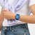 Swatch Armbanduhr blau am Handgelenk, rundes Zifferblatt mit Streifenmuster