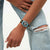 Damenuhr am Handgelenk: blau-schwarzes Armband, goldene Details, Schrift auf weißem Zifferblatt