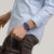 Swatch Armbanduhr am Handgelenk mit blauem Armband, rechteckigem Zifferblatt
