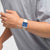 Swatch Armbanduhr getragen: quadratisches beiges Gehäuse mit blauem Zifferblatt am Handgelenk