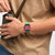 Swatch Armbanduhr am Handgelenk, grünes Armband, schwarzes Gehäuse, pinkes Zifferblatt