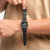 Schwarze Armbanduhr mit rechteckigem Zifferblatt und schwarzem Armband am Handgelenk