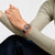 Armbanduhr am Handgelenk: Roségoldfarbenes Gehäuse, offen gestaltetes Zifferblatt, violettes Band.