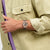 Armbanduhr am Handgelenk mit Roségoldfarbenem Gehäuse und offenem Uhrwerk, dunkelviolettes Band.