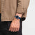 Armbanduhr am Handgelenk mit dunkelblauem Zifferblatt und blauem perforiertem Armband.