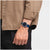Armbanduhr am Handgelenk: dunkelblaues Zifferblatt, blaues perforiertes Armband.