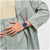 Armbanduhr am Handgelenk mit dunkelblauem Zifferblatt und blauem perforiertem Armband.