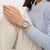 Armbanduhr am Handgelenk mit silbernem Mesh-Armband und grauem Zifferblatt