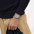 Armbanduhr am Handgelenk mit silbernem Mesh-Armband und grauem Zifferblatt
