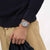 Armbanduhr am Handgelenk mit silbernem Mesh-Armband und grauem Zifferblatt