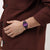 Swatch Damenuhr am Handgelenk: violettes Zifferblatt, schwarzes Armband mit Farbmuster