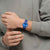 Armbanduhr am Handgelenk im grauen Hoodie: blaues Zifferblatt und blaues Band.