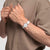 Swatch Armbanduhr am Handgelenk mit weißem Band und Details am Edelstahlgehäuse