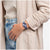 Swatch Armbanduhr am Handgelenk mit blauem Armband und rundem Zifferblatt