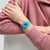 Damenuhr am Handgelenk mit türkisfarbenem Silikonarmband und blauem Zifferblatt